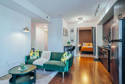 Bright and inviting living room featuring a plush green sofa, modern accents that flow to the dining nook